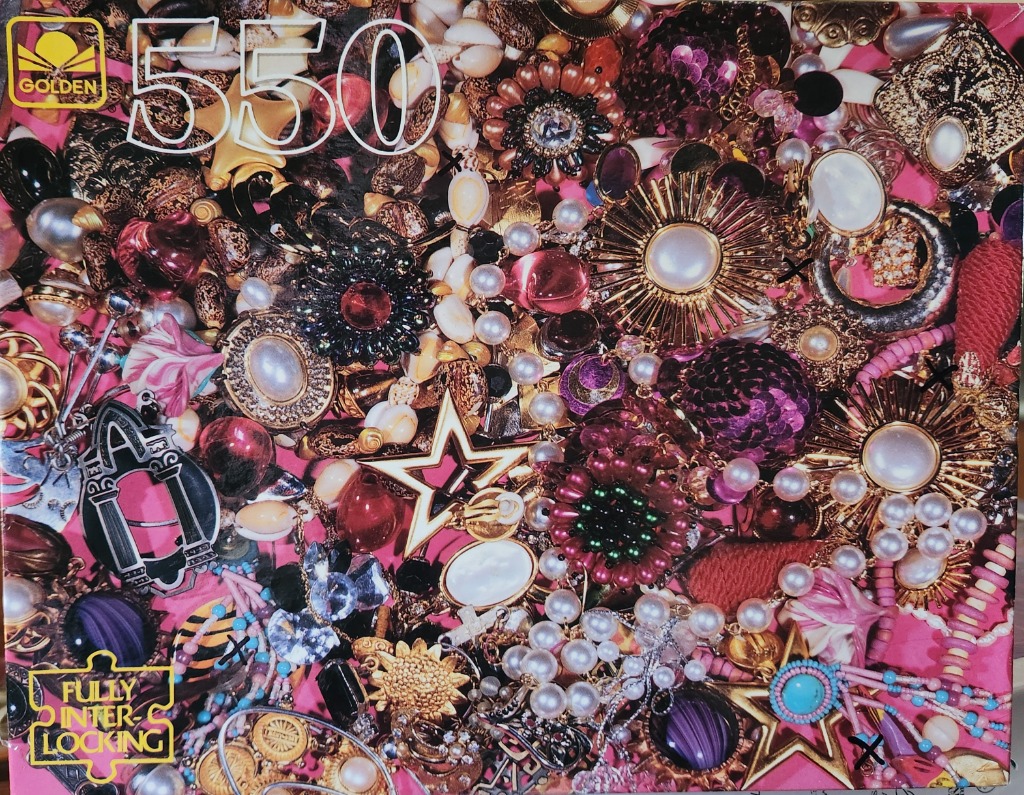 A dense, colorful collection of costume jewelry, brooches, and pearls scattered on a bright pink surface.