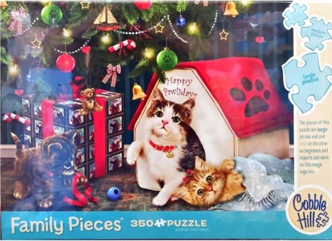 Two kittens playing in front of a festive dog house and a stack of Christmas gifts under a decorated tree.
