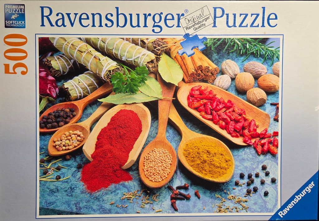 A collection of spices, herbs, and seasonings in wooden spoons arranged on a blue textured surface.