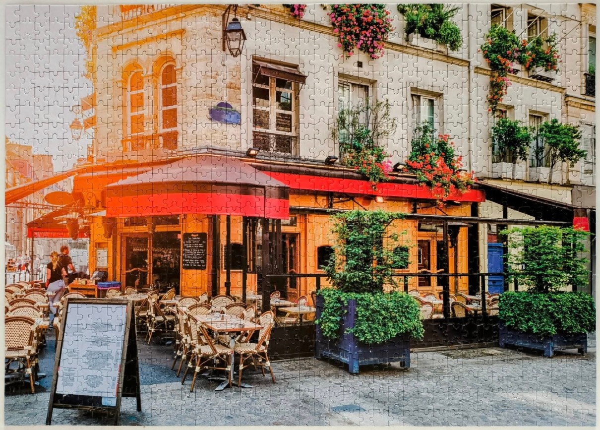 A charming Parisian-style street cafe with red awnings and cobblestone terrace