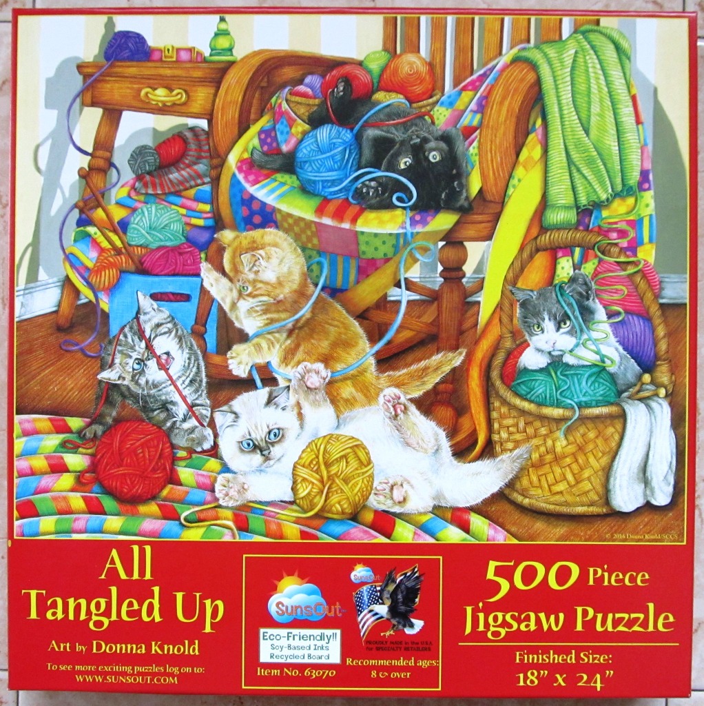 Five kittens playing with colorful yarn balls in a cozy room with a wooden rocking chair.