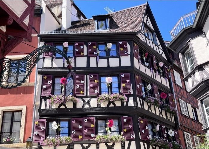 A three-story half-timbered building adorned with heart decorations and flower boxes in a European town.
