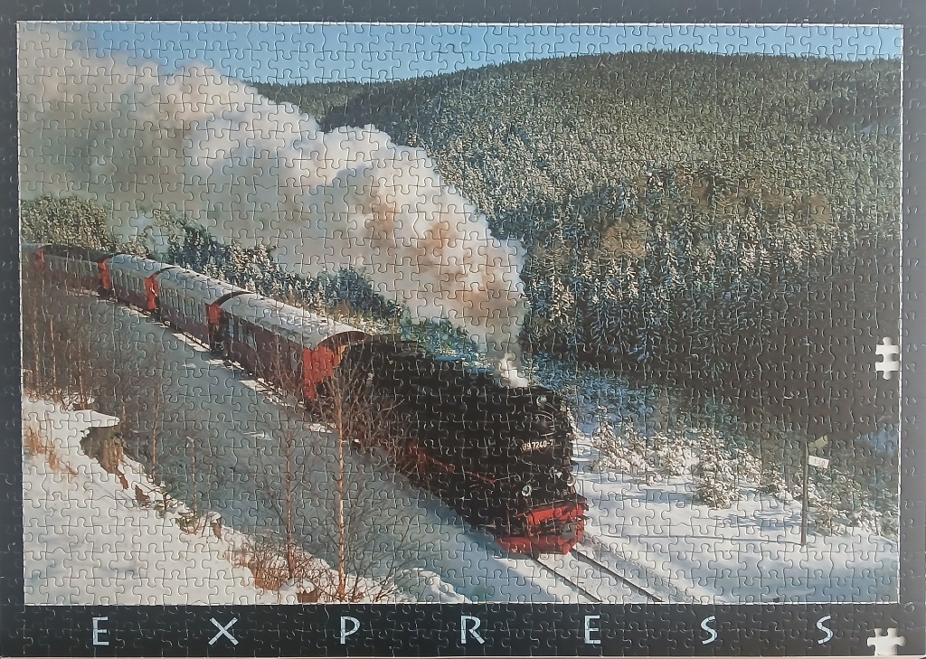 A steam locomotive pulling passenger cars through a snow-covered evergreen forest.