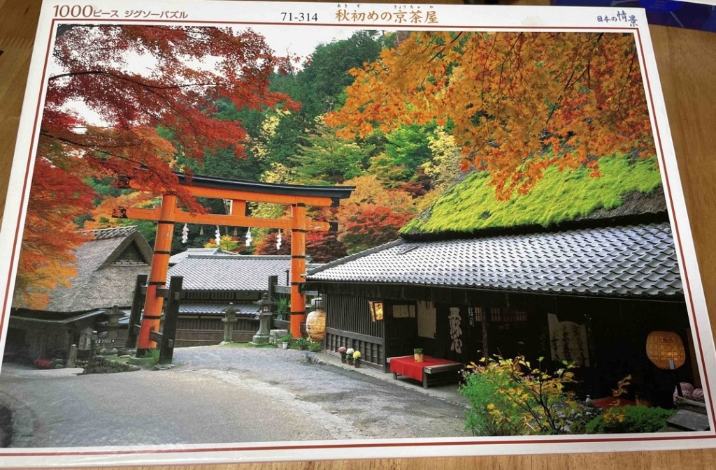 A traditional Japanese teahouse and bright orange torii gate surrounded by vibrant autumn foliage.