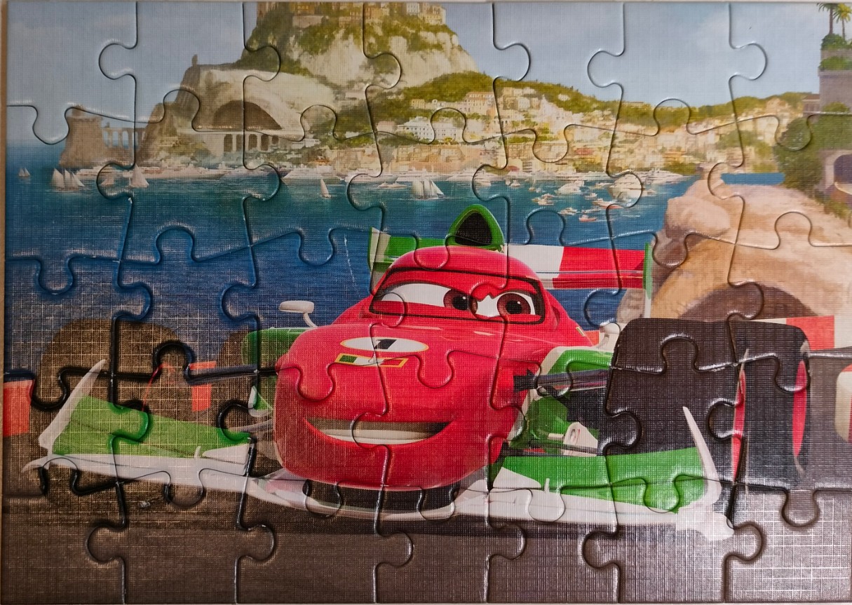 A red race car with Italian flag colors driving along a seaside town coastline in a cartoon art style.