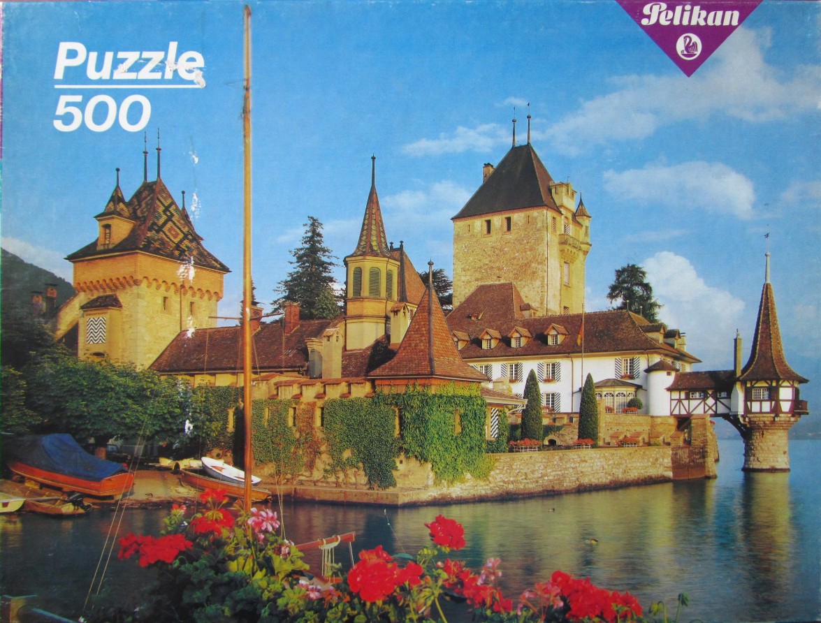 The medieval Oberhofen Castle on Lake Thun in Switzerland with bright red geraniums in the foreground.