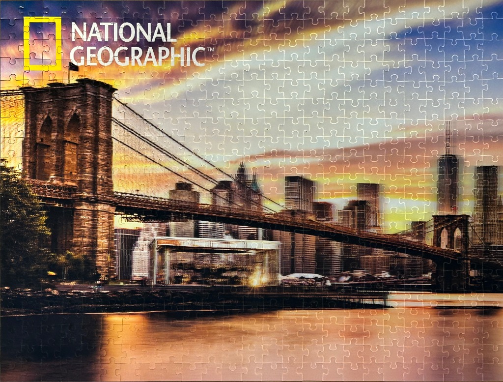 Brooklyn Bridge at sunset with NYC skyline and warm, colorful sky.