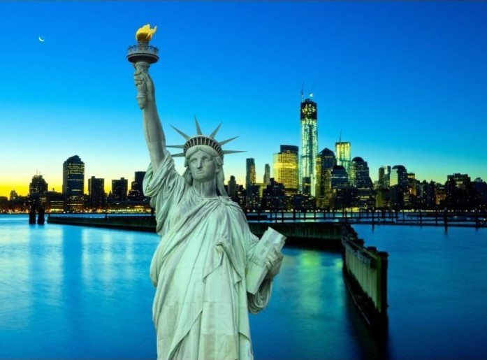 The Statue of Liberty standing before a New York City skyline at dusk