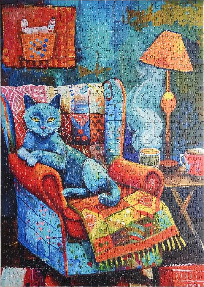 An illustration of a blue cat lounging in a colorful patchwork armchair with a lamp and a steaming mug nearby.