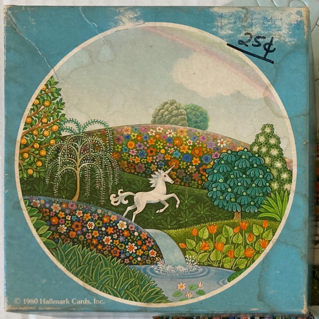 A whimsical 1980s illustration of a white unicorn leaping over a small waterfall in a lush, floral meadow.