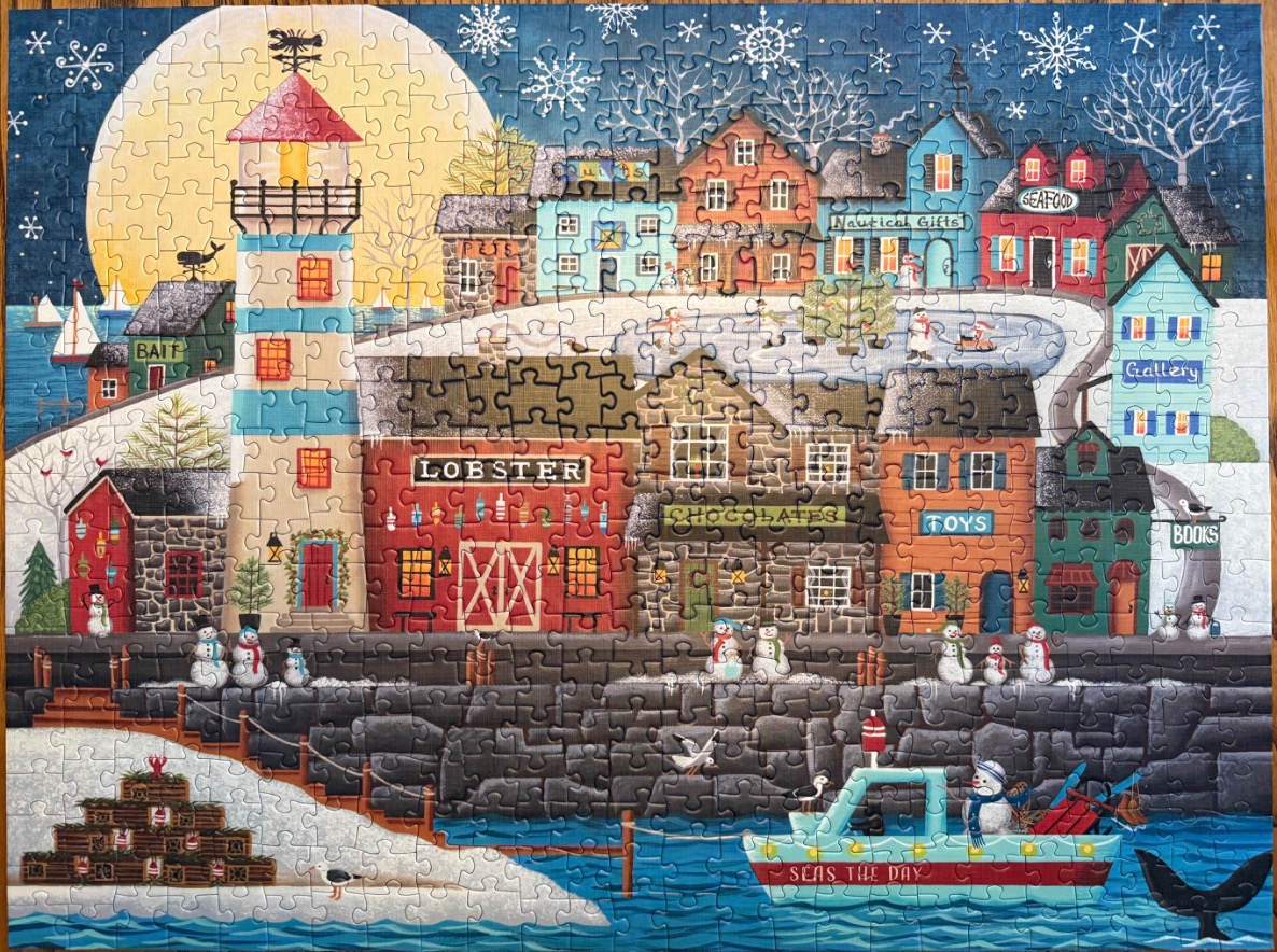 Coastal village with lighthouse and snowmen under a full moon and snowflakes.