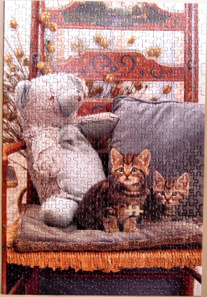 Two tabby kittens sitting on a chair next to a large teddy bear