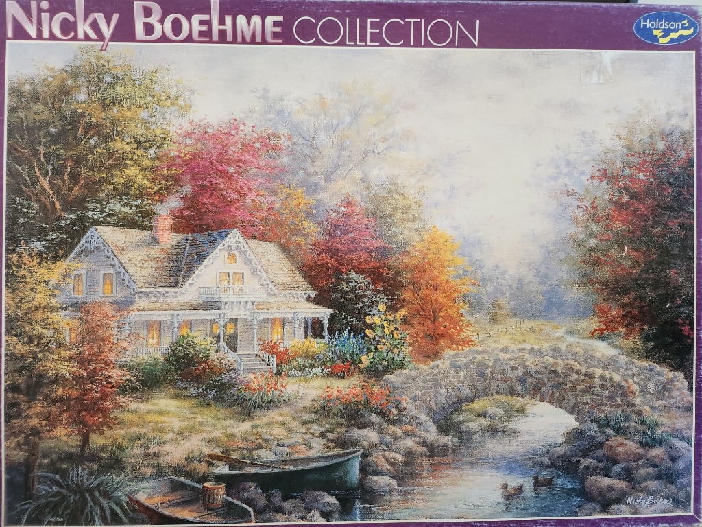 An idyllic white cottage nestled in an autumn forest beside a stone bridge and a calm stream.