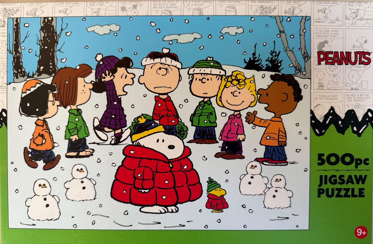The Peanuts gang including Snoopy and Woodstock standing in the snow surrounded by small snowmen.