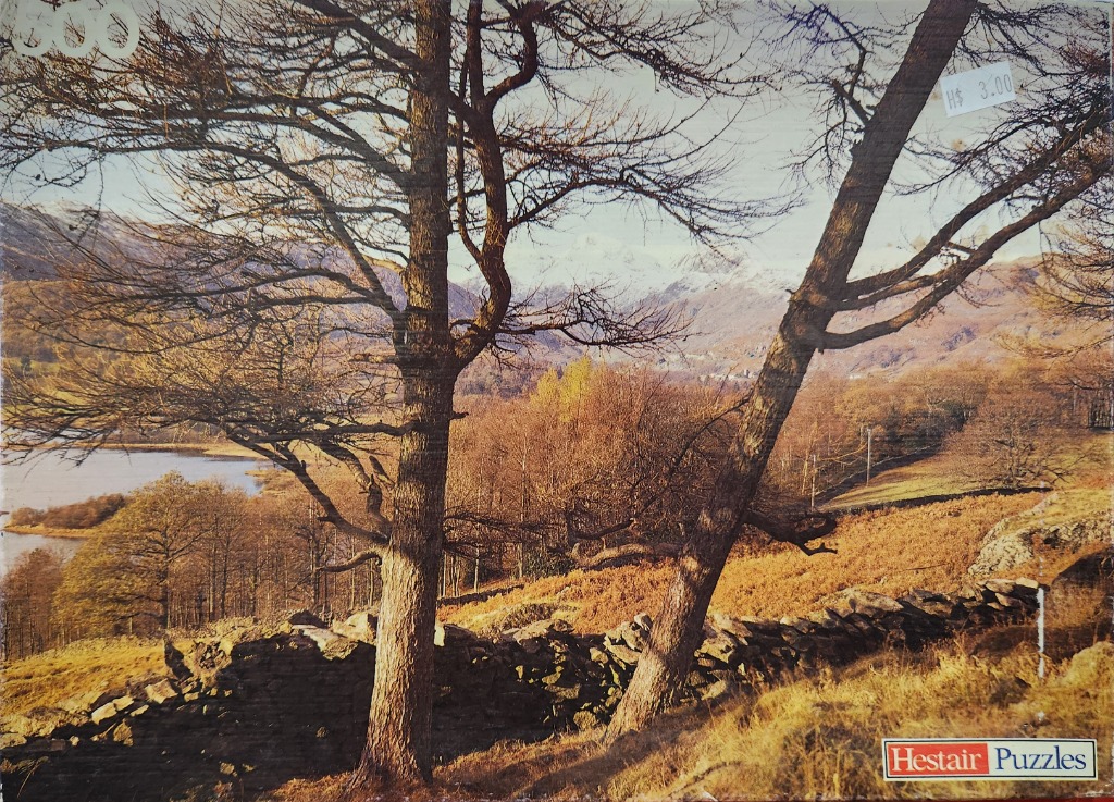 A peaceful, sunlit landscape featuring two prominent trees in the foreground, a dry-stone wall, and a lake with mountains.