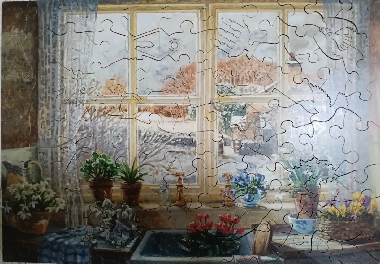 Interior view of a window overlooking a snowy landscape with potted flowers on the sill.