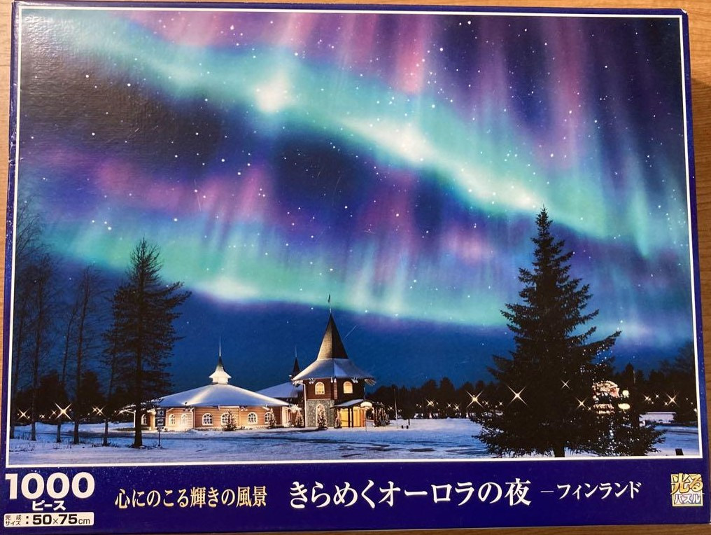 A serene Finnish winter scene at night under a vibrant display of the aurora borealis above a snow-covered building.