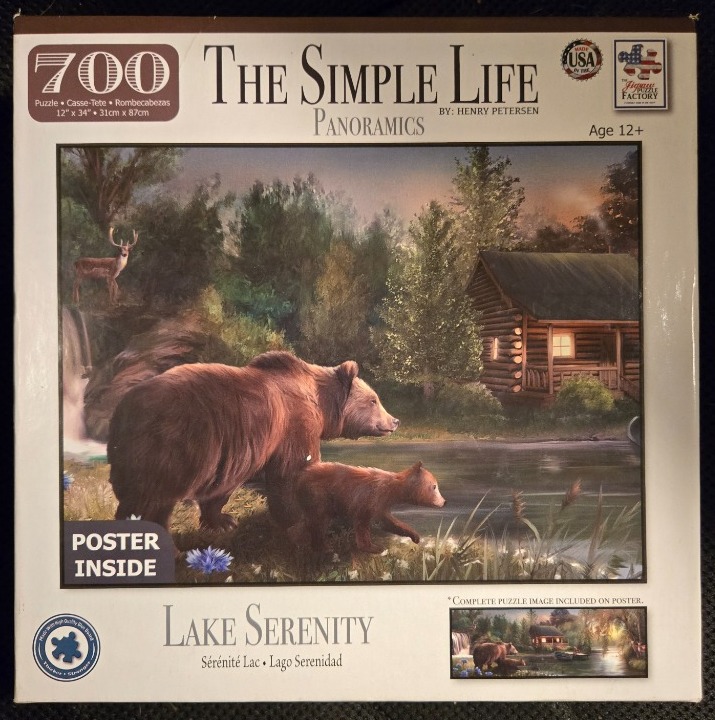 A grizzly bear and her cub walk along a lake shore near a glowing cabin at twilight.