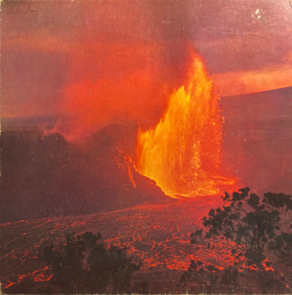 Volcanic eruption with a massive fountain of lava glowing against a dark twilight sky.
