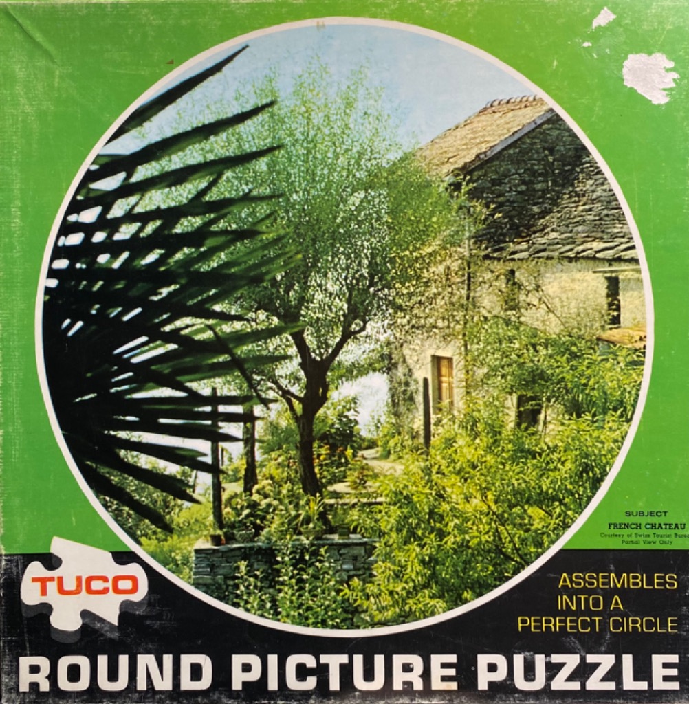 A circular photograph of a French stone chateau surrounded by lush green foliage and trees.