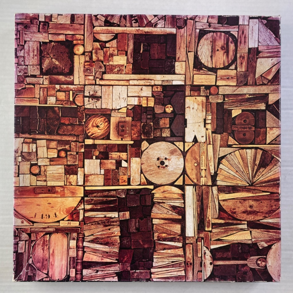 A collage of various wooden scraps, blocks, and circular shapes in a rustic, mosaic-like arrangement.