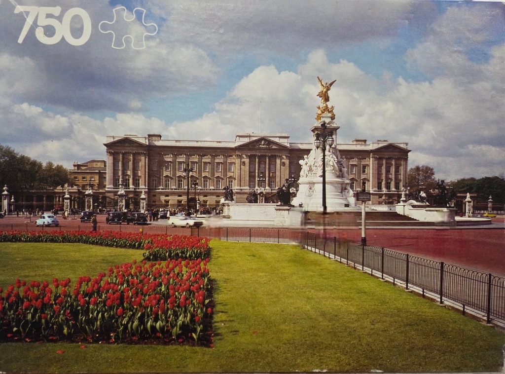 A vintage photograph of Buckingham Palace and the Victoria Memorial with red tulips in the foreground.