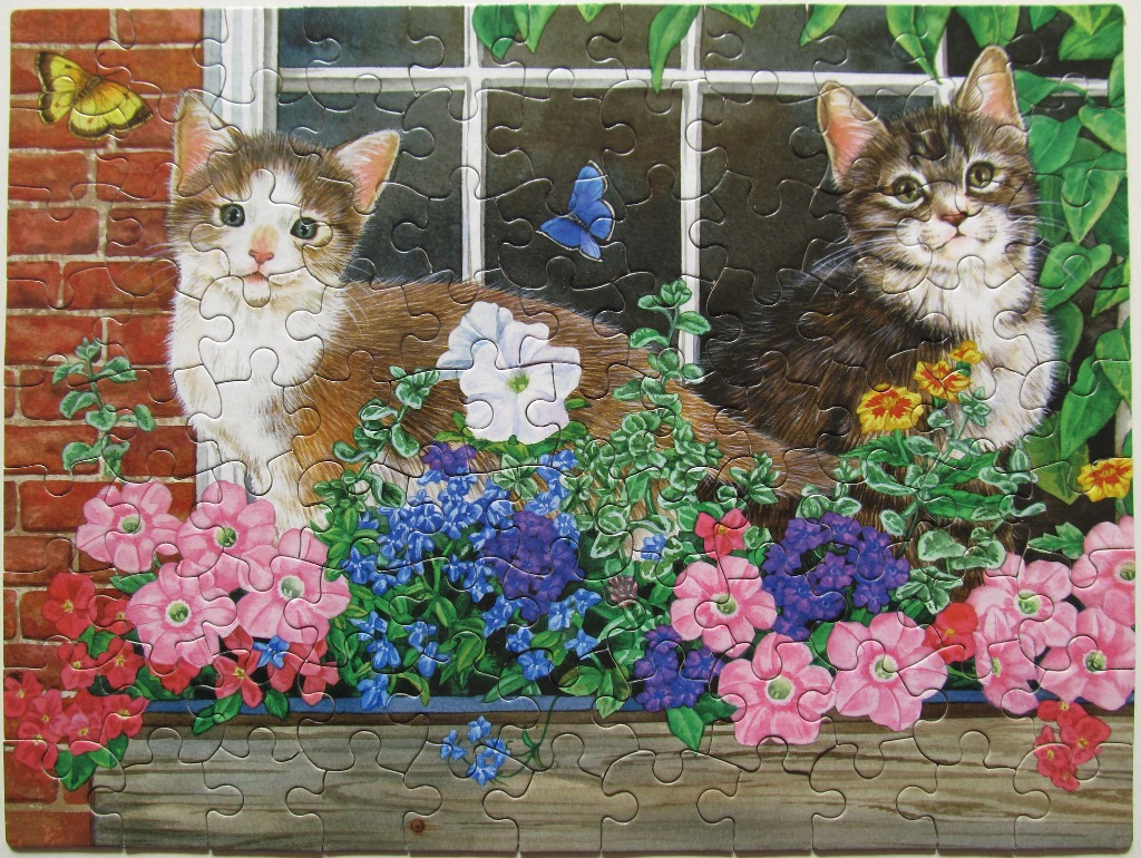 Two kittens sitting in a window box filled with colorful flowers.