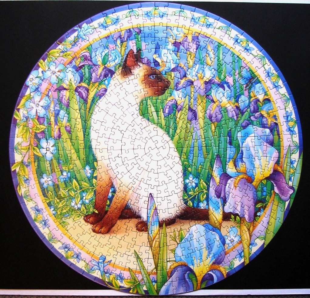 Circular illustration of a Siamese cat sitting among purple irises in a garden.