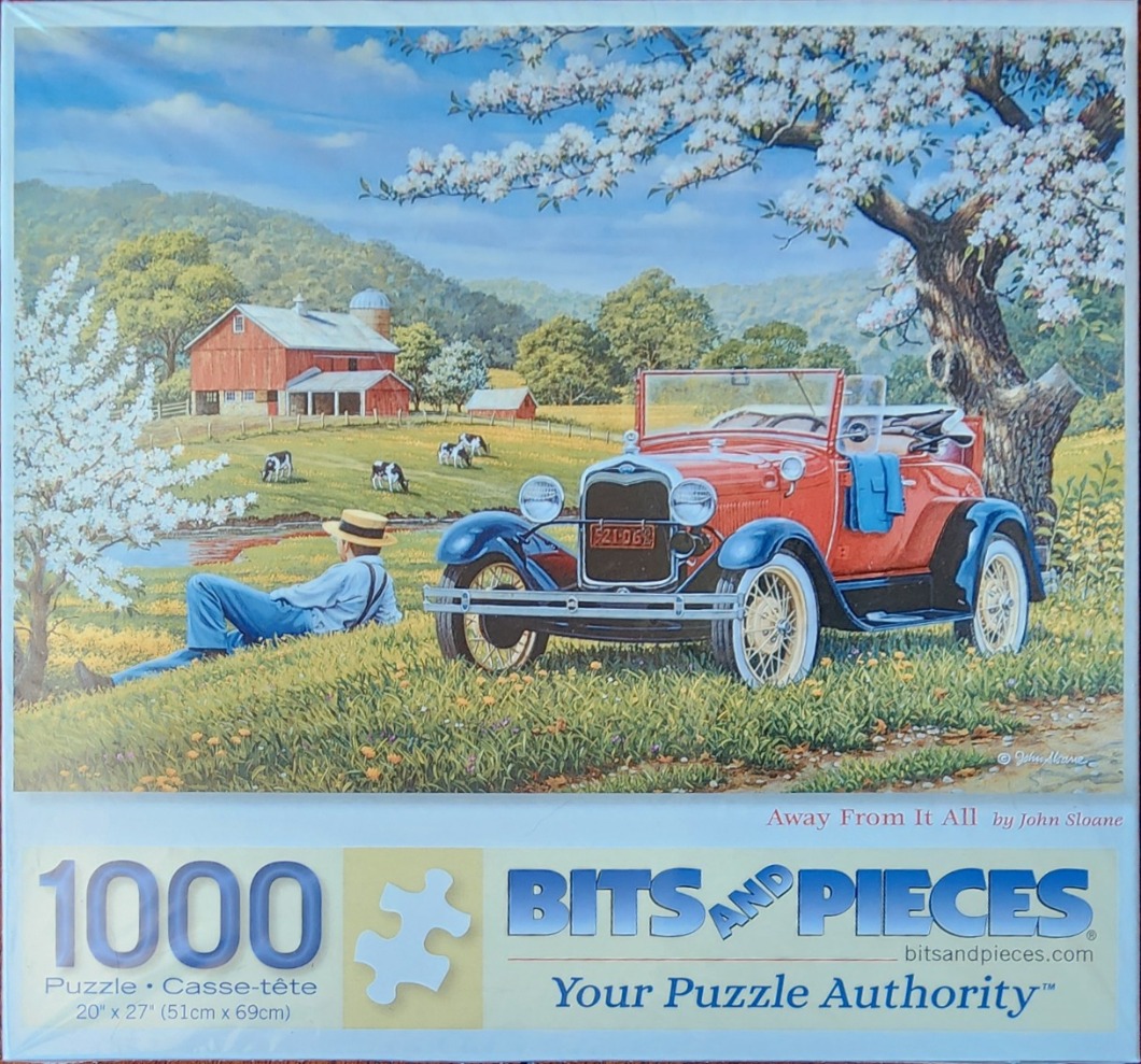 A vintage red car parked in a spring meadow with a man resting under a blossoming tree and a red barn in the distance.