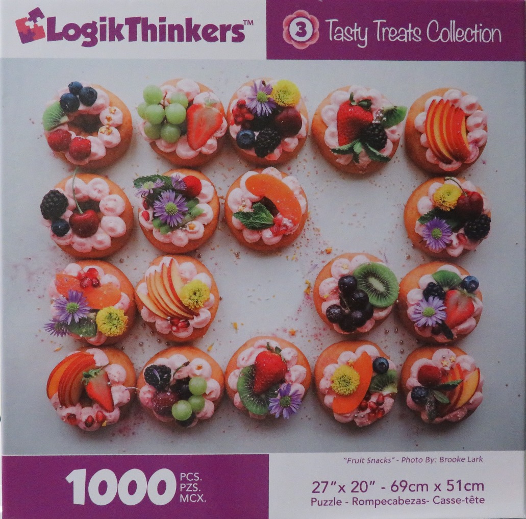 A top-down photograph of sixteen donuts decorated with pink frosting, fresh fruit, and small flowers, arranged in a grid.