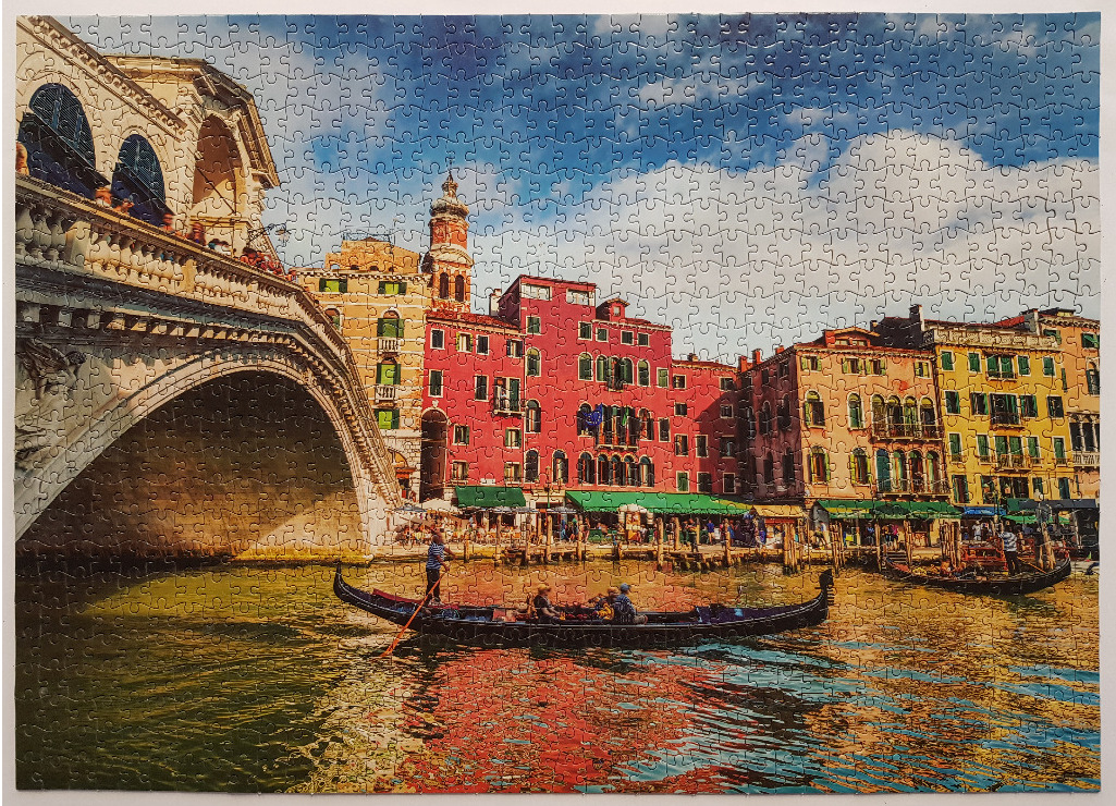 A gondola traveling under the Rialto Bridge in Venice on a sunny day.