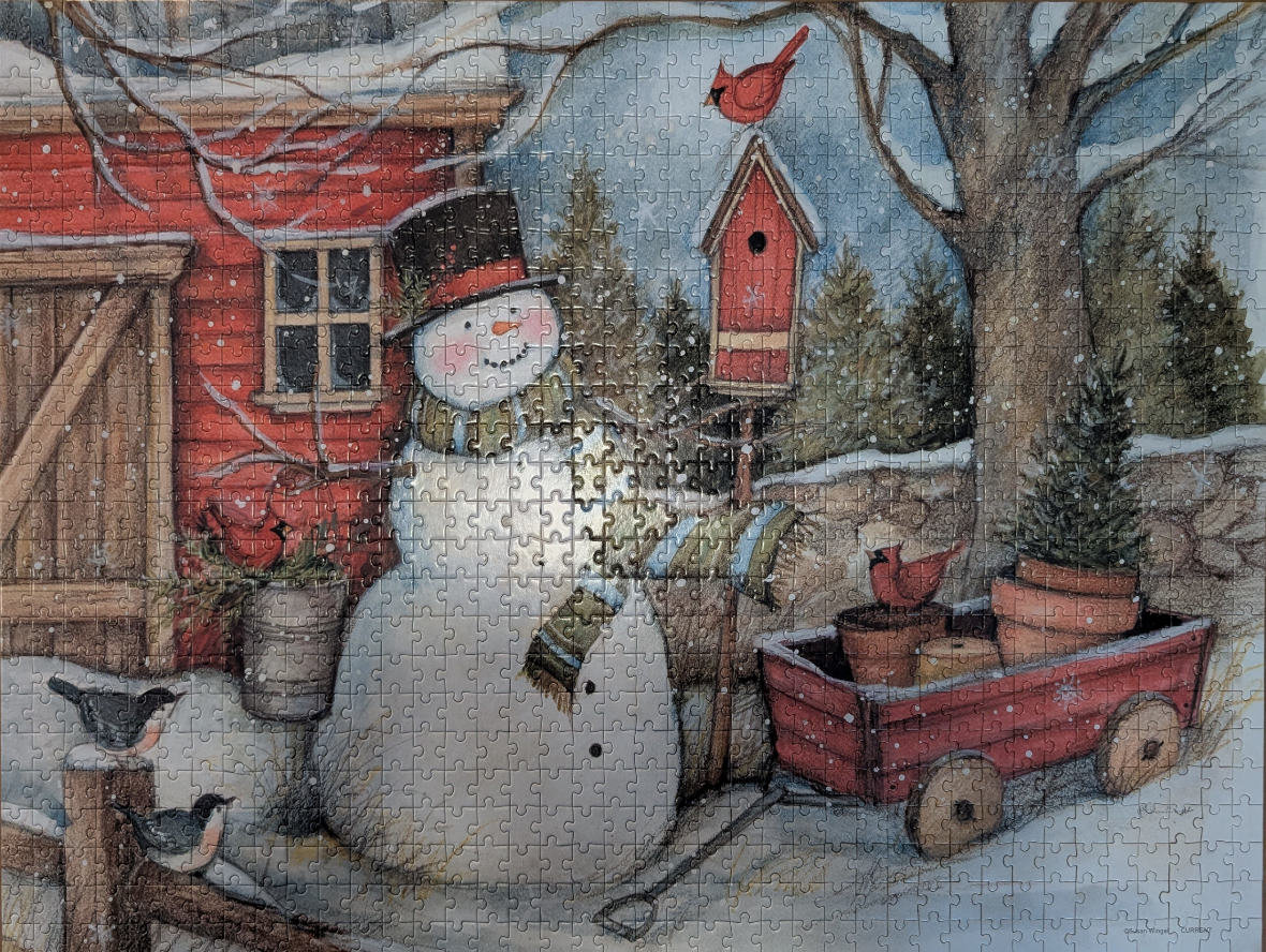 A snowman wearing a top hat and scarf stands in a snowy scene next to a red barn, a birdhouse, and a wagon.