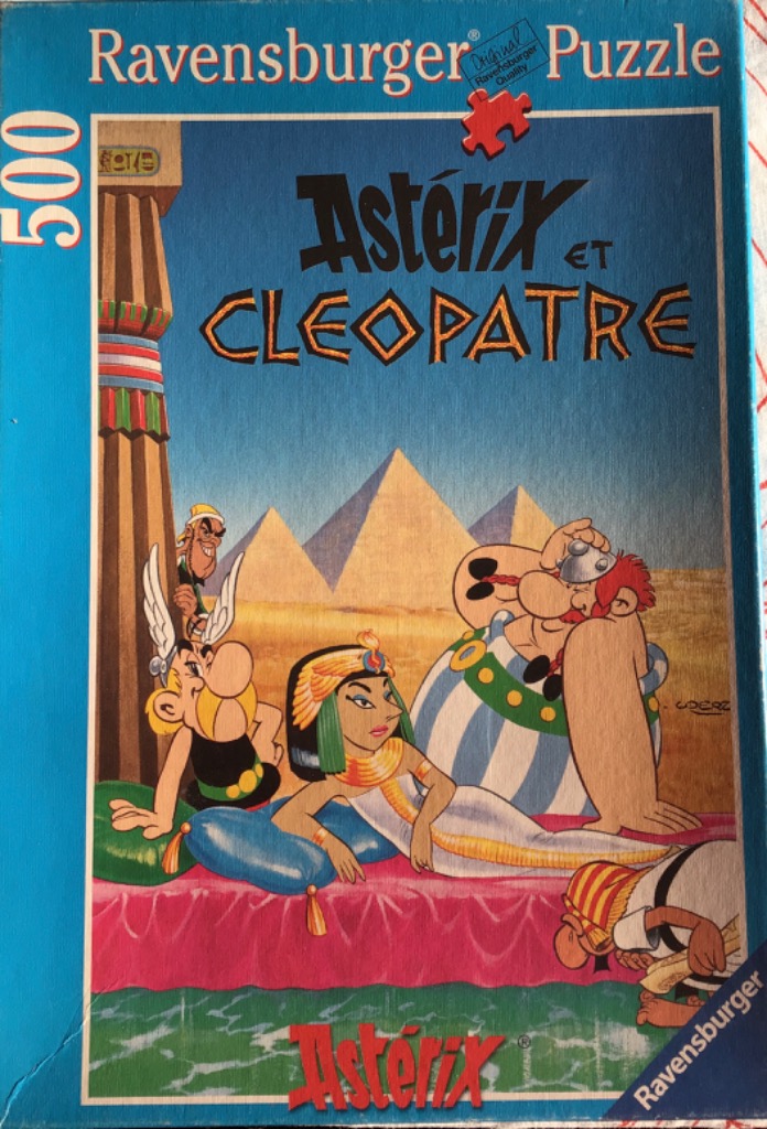 Cartoon illustration of Asterix, Obelix, and Cleopatra in front of Egyptian pyramids.