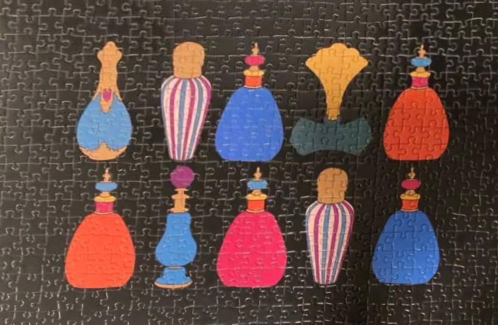 A collection of ten decorative vintage-style perfume bottles in bright colours arranged against a black background.