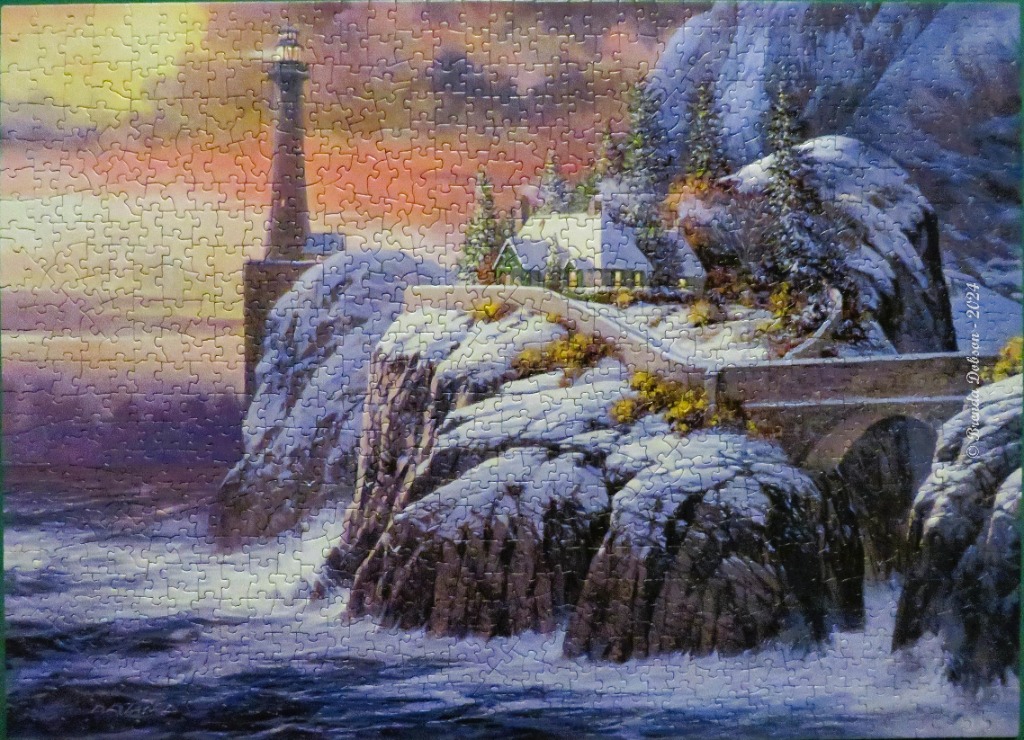 A lighthouse and snow-covered cottage on a rocky coastal cliff at sunset.