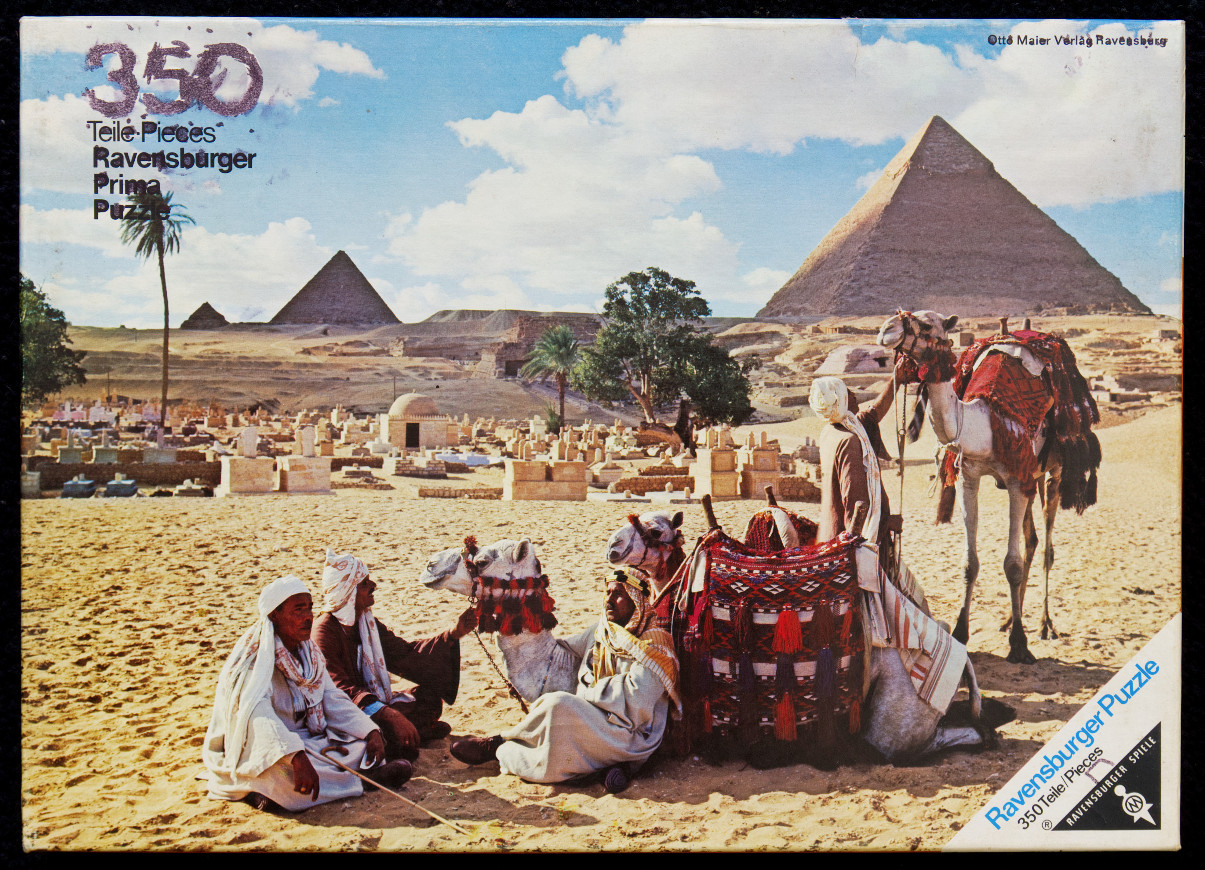 Men in traditional clothing with camels in front of the Great Pyramids of Giza