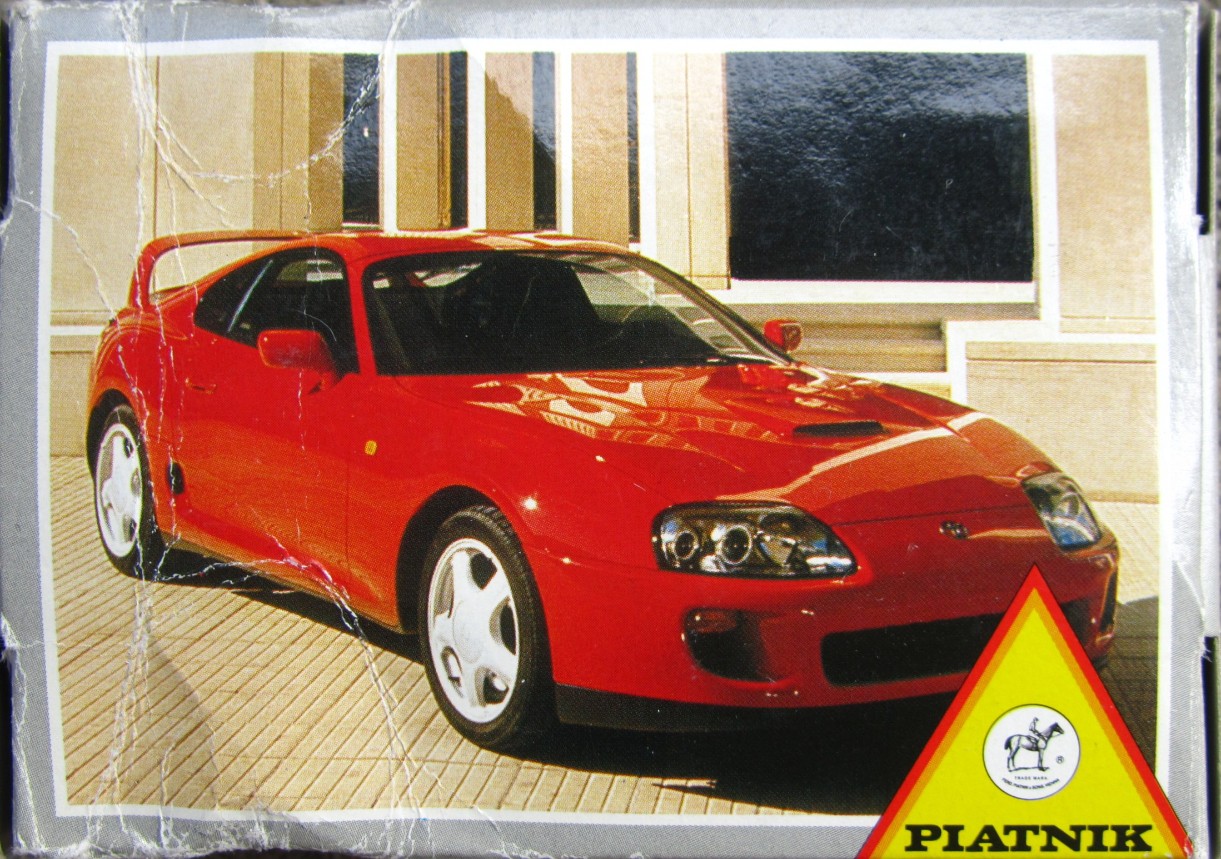 A red sports car parked in front of a modern building with large windows.