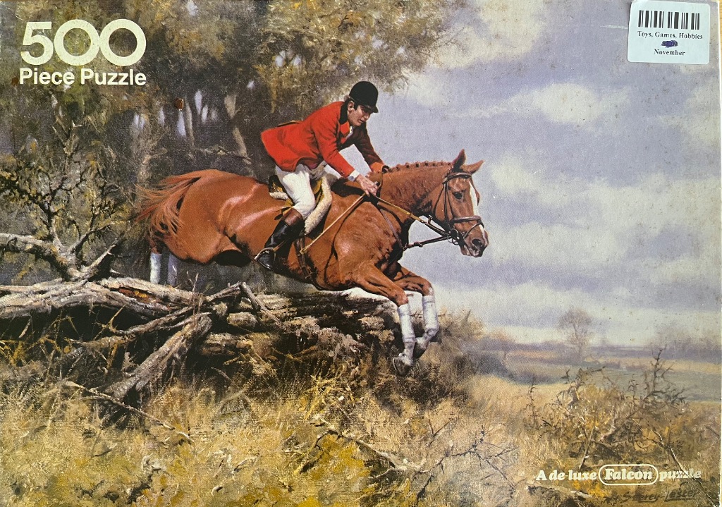 A fox hunter on a chestnut horse jumping over a rustic wooden fence in a countryside setting.