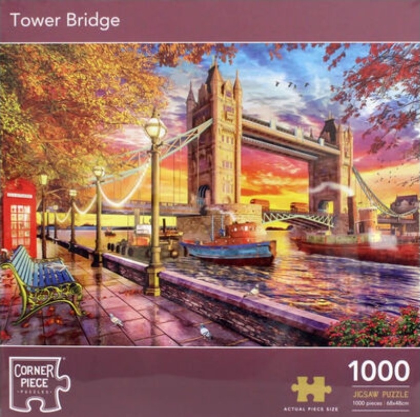 Tower Bridge in London during an autumn sunset with a red phone booth and river boats in the foreground.