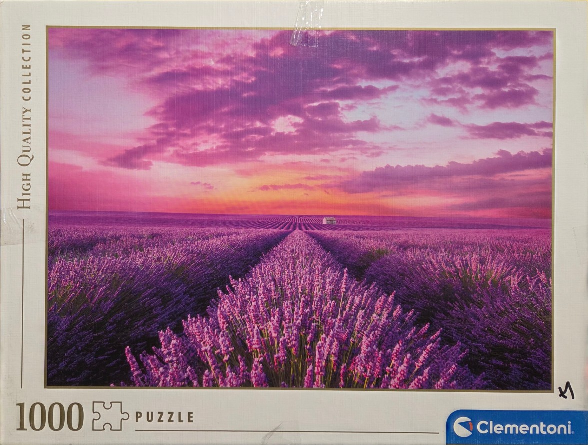 A vast field of purple lavender under a vibrant pink and orange sunset sky.