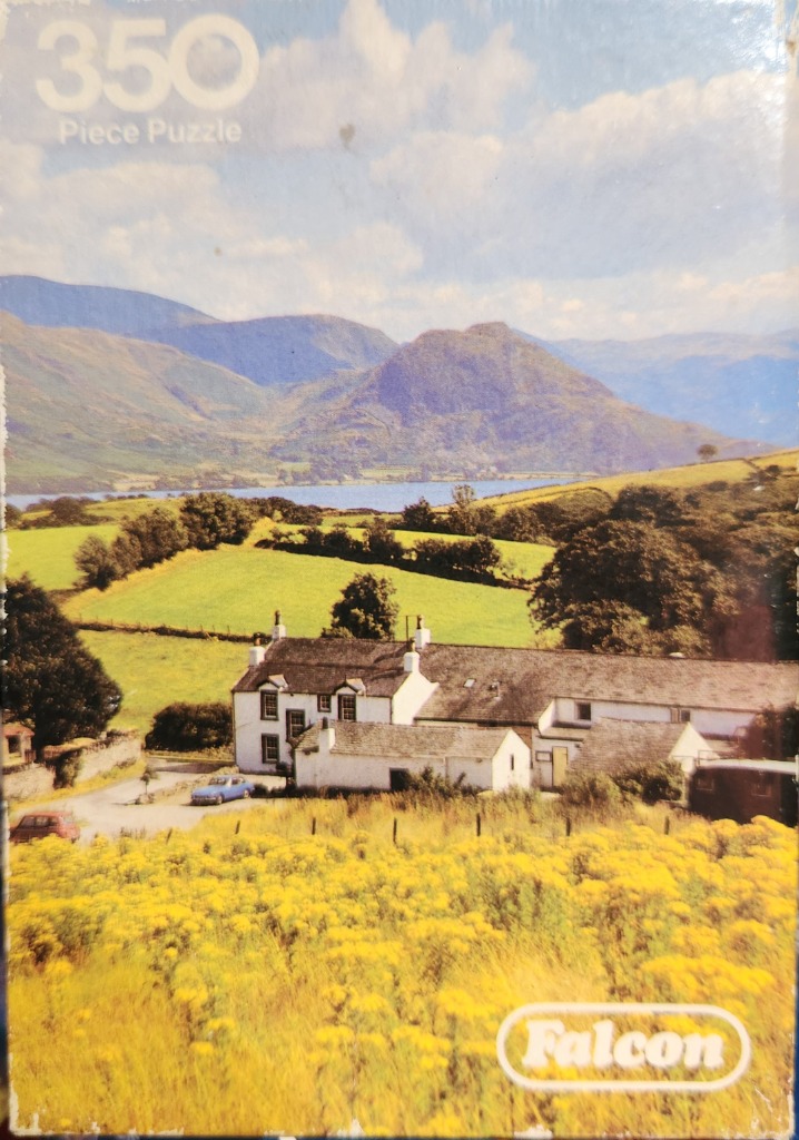 A scenic photograph of a white farmhouse nestled in a valley with bright yellow wildflowers in the foreground.