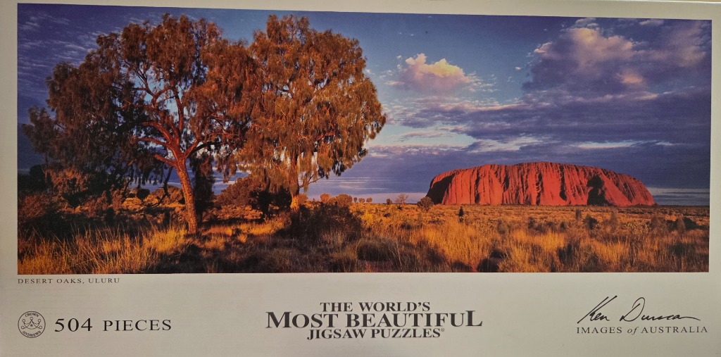 Landscape photograph of Uluru at sunset with desert oaks in the foreground.
