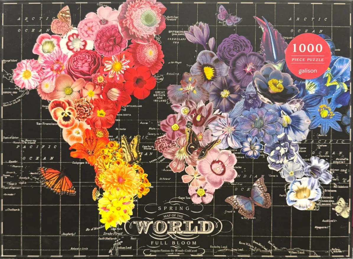 A world map composed of colorful flower clusters arranged to represent continents over a black grid background.