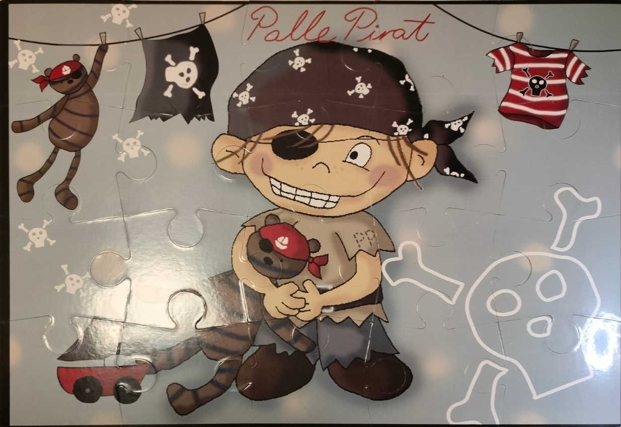 Cartoon illustration of a pirate boy named Palle Pirat holding a teddy bear with a pirate theme.
