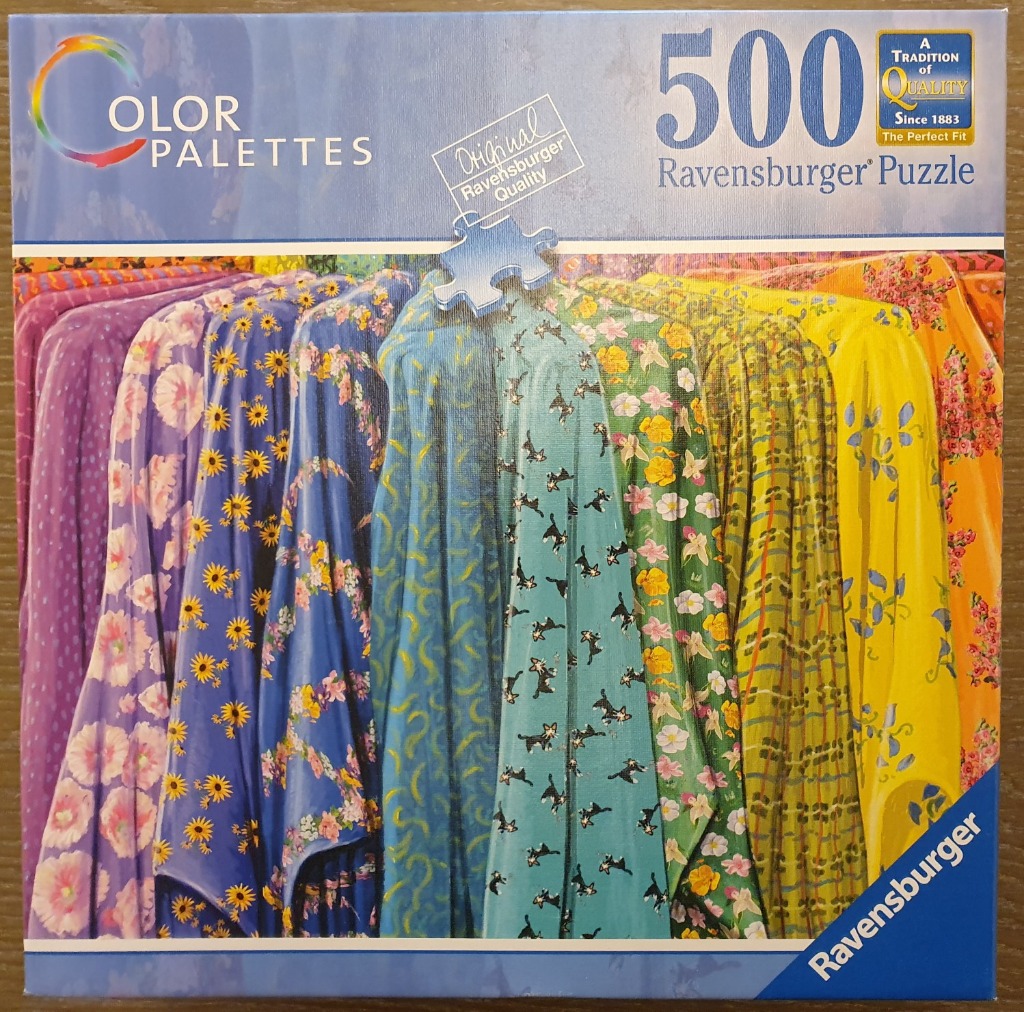 A row of colorful patterned fabrics hanging vertically in a gradient of purple to orange.