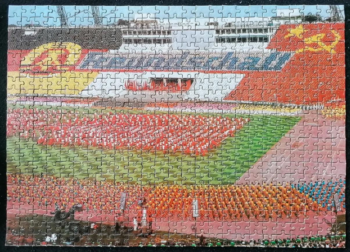 A panoramic view of a large-scale East German socialist sports celebration in a stadium.