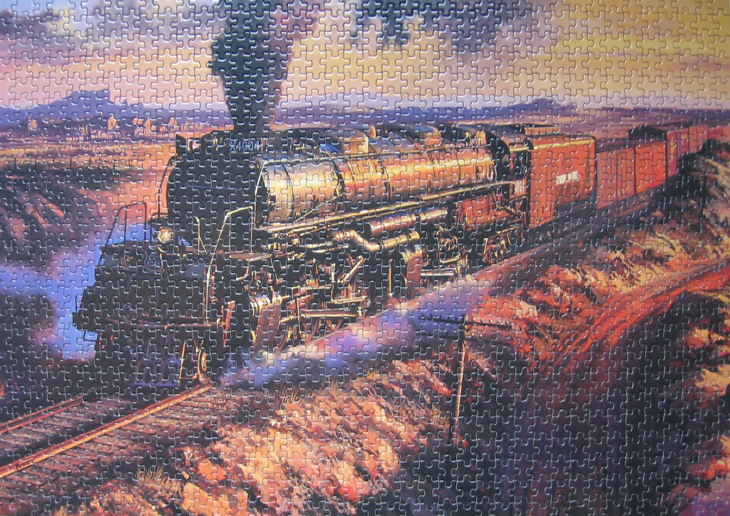 A steam locomotive pulling train cars through a desert landscape at sunset.