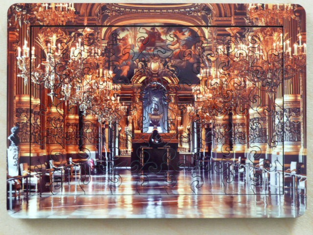 An opulent, dimly lit interior of a grand historic ballroom featuring ornate gold columns, chandeliers, and high ceilings.
