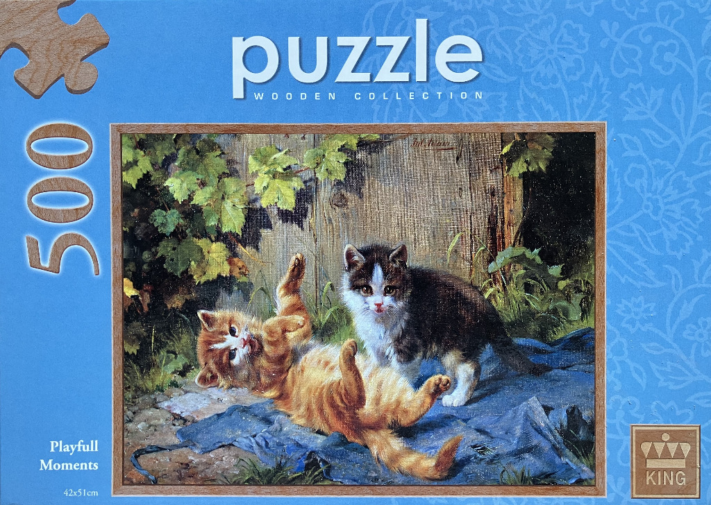 Two kittens, one orange and one black and white, playing on a blue blanket in a garden setting.