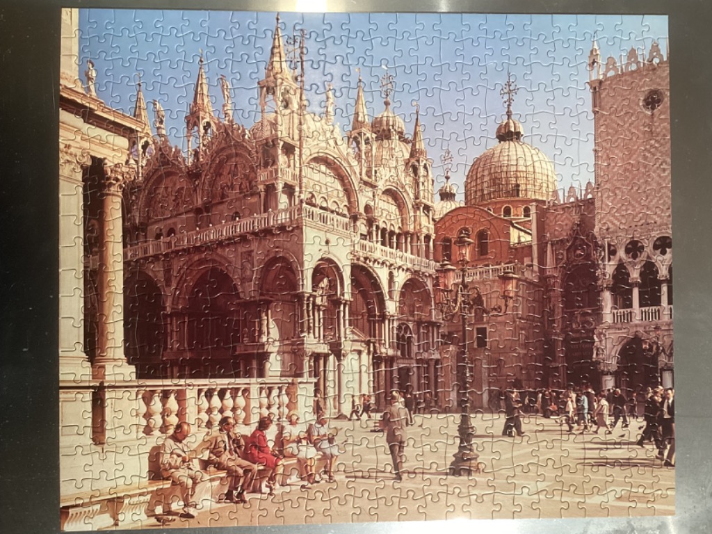 St. Mark's Basilica in Venice bathed in warm sunlight with people in the square below.